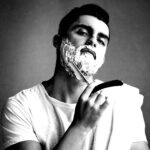Un homme se rase avec de la mousse et un rasoir
