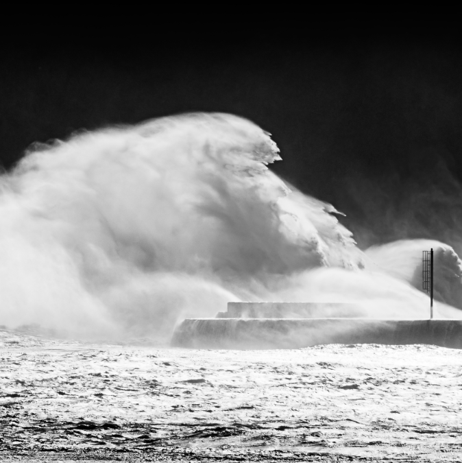 Photo d'un vague tempétueuse se fracassant sur un quai